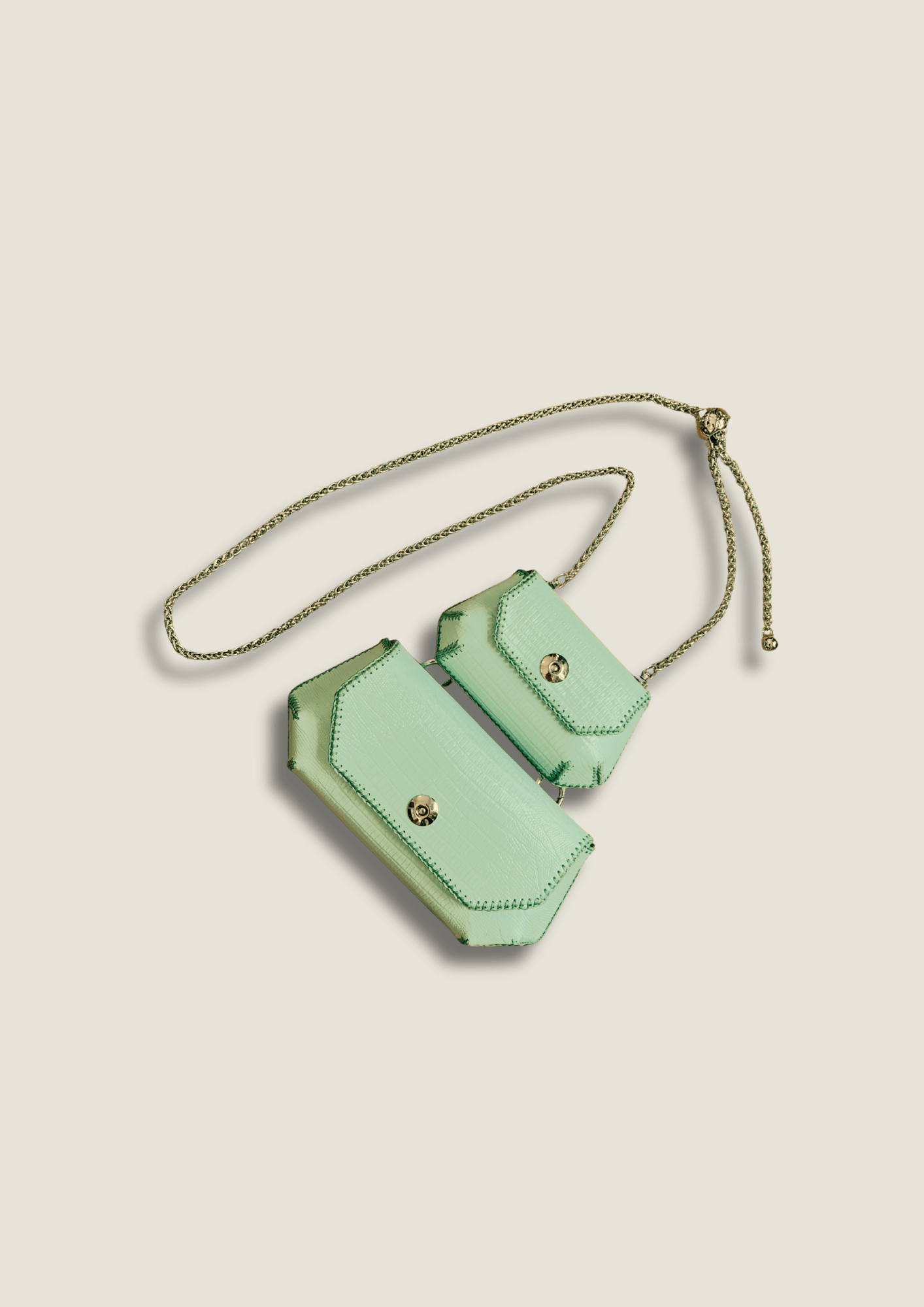 Mint green crossbody bag with gold accents on a beige background